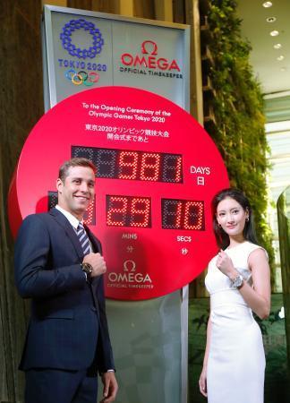 　東京・銀座に設置されたオメガの東京五輪カウントダウン時計の前でポーズをとるチャド・レクロー選手（左）と女優の菜々緒さん＝１６日午前