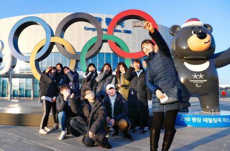 　韓国・平昌冬季五輪開幕まで１カ月となる中、開催地の江陵駅に設置された五輪マーク前で記念撮影する学生ら＝９日（共同）
