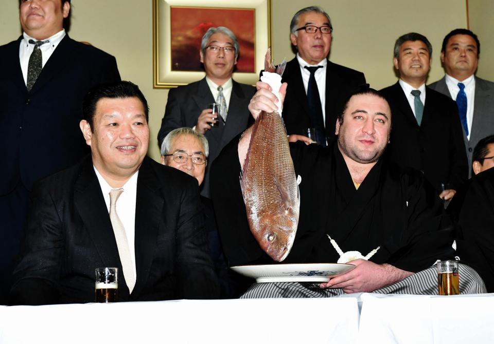 春日野親方（左）の横でタイを持ち上げる栃ノ心（撮影・西岡正）