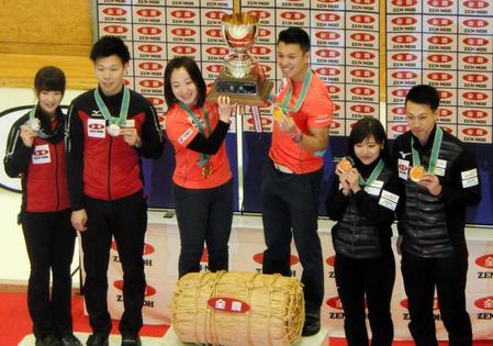 　表彰台で優勝カップを掲げる藤沢（中央左）、山口（中央右）ペア、左は２位のチーム平田、右は３位の吉田知、清水ペア