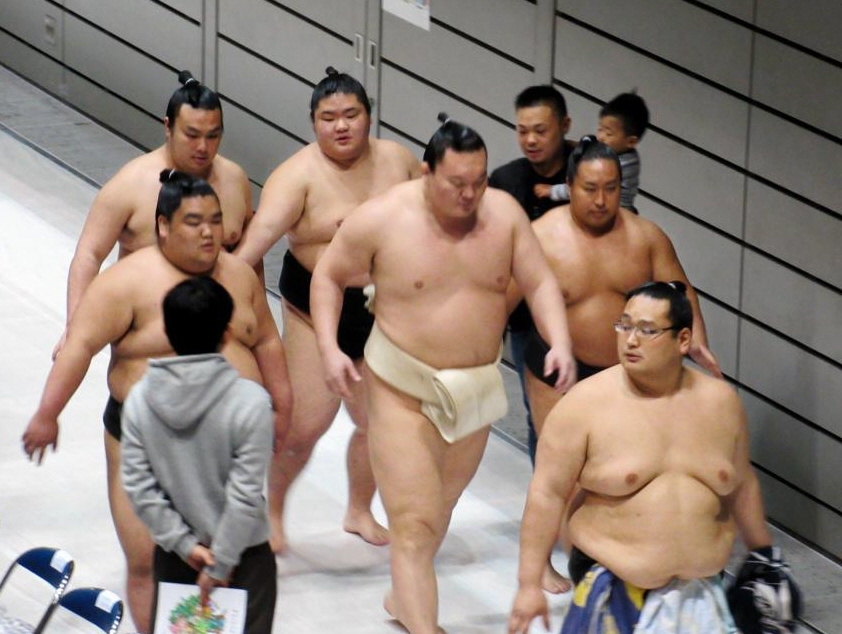 付け人に囲まれ稽古場に入る白鵬（中央）