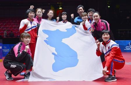 　卓球世界選手権団体戦を終え、統一旗を囲みポーズをとる女子の南北合同チーム「コリア」＝５月、スウェーデンのハルムスタード