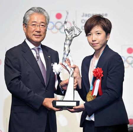 日本オリンピック委員会の竹田恆和会長（左）から最優秀賞のトロフィーを受け取る小平奈緒（撮影・開出牧）