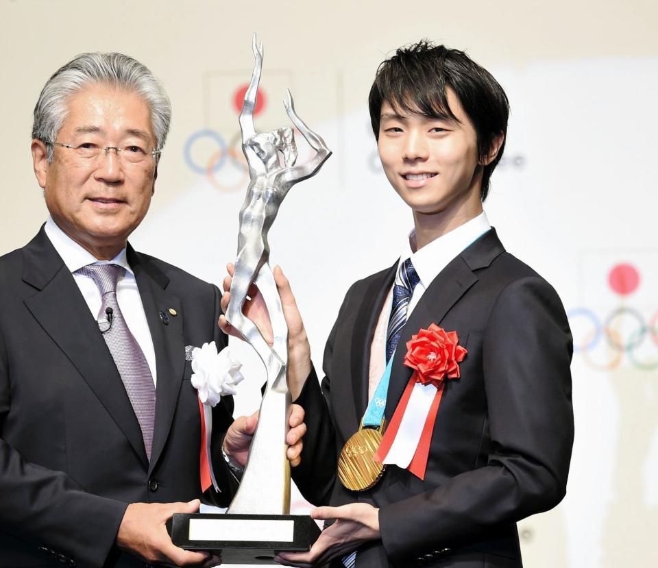 日本オリンピック委員会の竹田恆和会長（左）からトロフィーを受け取り笑顔の羽生結弦＝都内