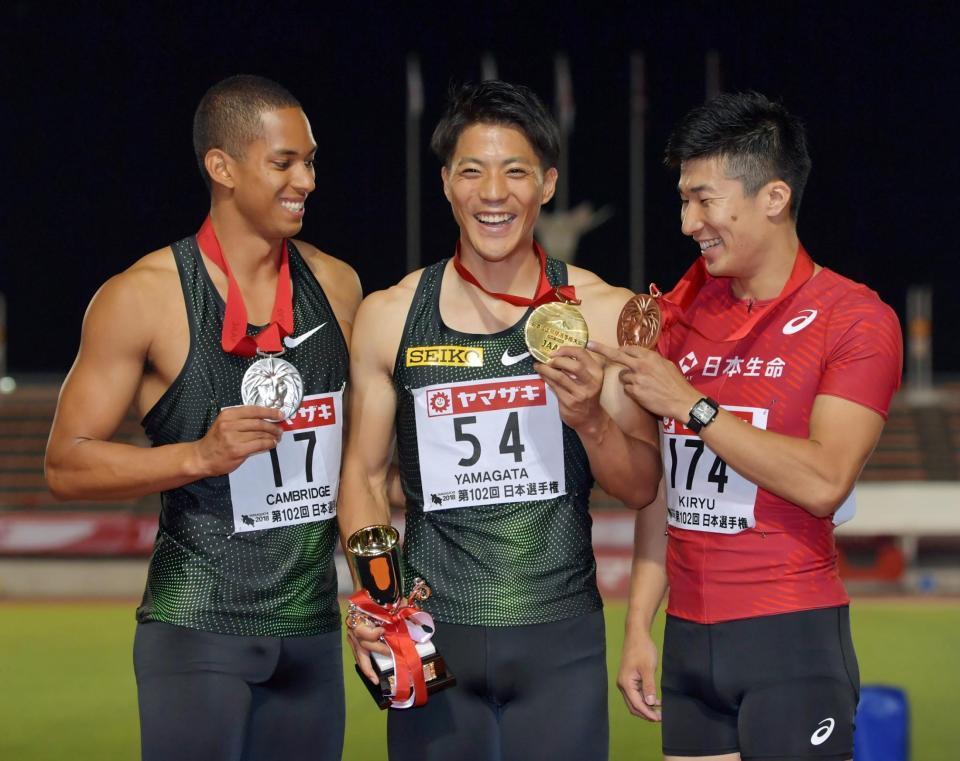 男子１００メートルの表彰式で山県亮太（写真中央）金メダルを見つめる２位のケンブリッジ飛鳥（同左）と３位の桐生祥秀