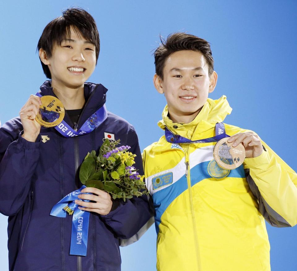 　２０１４年２月、ソチ五輪フィギュアスケート男子の表彰式でメダルを掲げる銅のデニス・テン選手（右）と金の羽生結弦選手（共同）