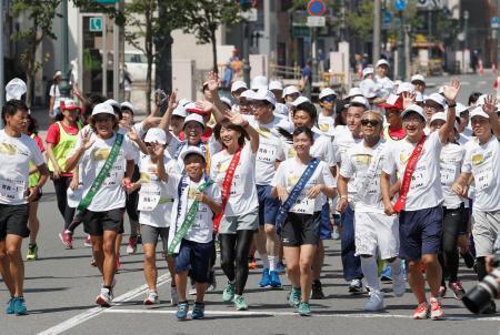 　「未来への道　１０００ｋｍ縦断リレー」がスタートし、青森市内を走る女子マラソンの高橋尚子さん（前列中央）と参加者＝２４日午前、青森市