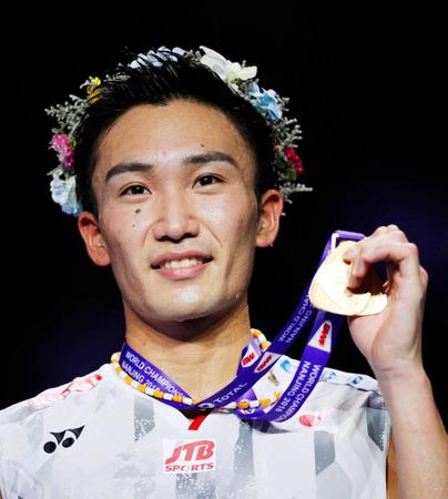 　日本男子初の金メダルを獲得し、表彰式でメダルを掲げる桃田賢斗（共同）