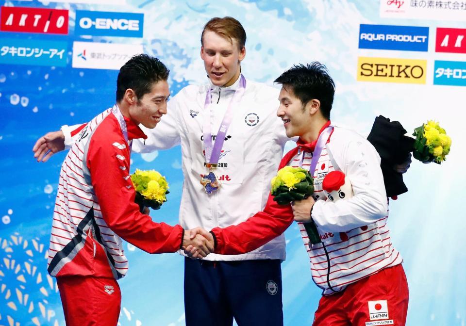 　男子４００メートル個人メドレーの表彰式で握手する２位の萩野公介（左）と３位の瀬戸大也。中央は優勝したチェース・ケイリシュ（共同）