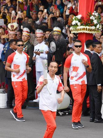 　大統領宮殿の敷地内でアジア大会の聖火リレーをするインドネシアのジョコ大統領（手前）＝１７日、ジャカルタ（共同）