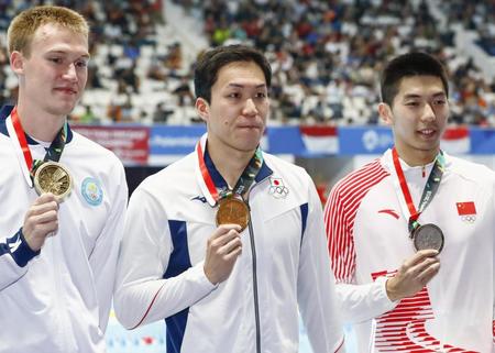 　男子１００メートル平泳ぎで優勝し、金メダルを手にする小関也朱篤（中央）＝ジャカルタ（共同）