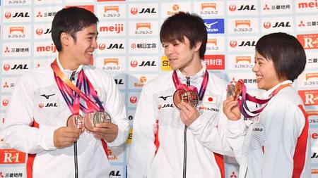 　３つのメダルを提げた白井健三（左）を、じっと見つめる内村航平（中央）と村上茉愛