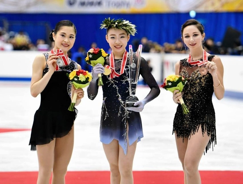 　優勝し笑顔を見せる紀平梨花（中央）。左は２位の宮原知子、右は３位のエリザベータ・トゥクタミシェワ（撮影・持木克友）