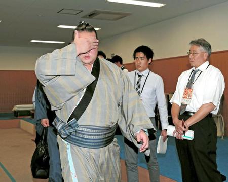 　無数のフラッシュを浴び顔を覆って支度部屋から引き揚げる稀勢の里（撮影・坂部計介）