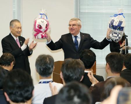 　２０２０年東京五輪・パラリンピック組織委事務局を訪れ、笑顔で大会マスコットを手にするＩＯＣのバッハ会長。左は森喜朗会長＝２８日午後、東京都港区