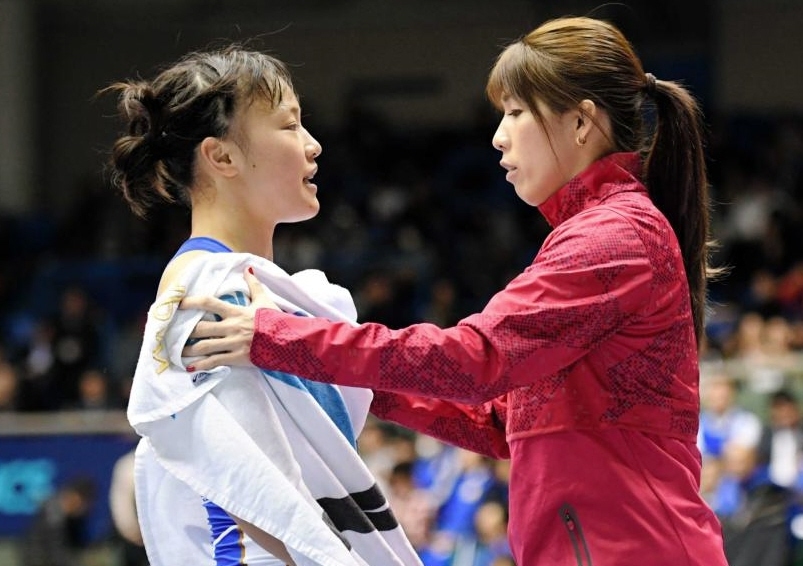 　ハーフタイムにセコンドについた吉田沙保里（右）から汗を拭いてもらう登坂絵莉＝２０１８年１２月