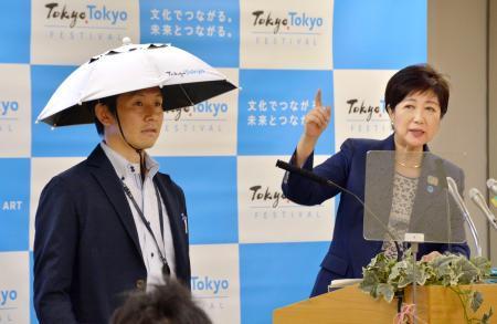 　かぶるタイプの傘について説明する東京都の小池百合子知事（右）＝２４日午後、東京都庁