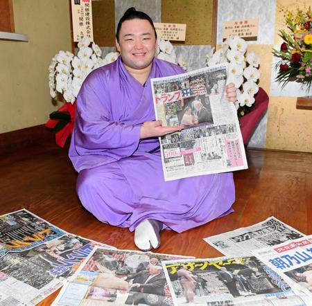 本紙を手に取り笑顔の朝乃山＝高砂部屋（撮影・棚橋慶太）