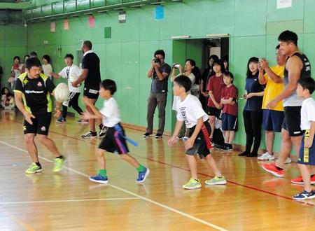 ラグビー日本代表が網走小を訪問。小学生とパスをするＳＨ田中（左）
