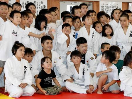 　母校の天理大で行われたイベントで、子どもたちと記念撮影する丸山城志郎（２列目左から３人目）、大野将平（同４人目）