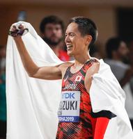陸上世界選手権の男子50キロ競歩で優勝し、日の丸を背に笑顔の鈴木雄介。東京五輪代表に決まった＝29日、ドーハ（共同）