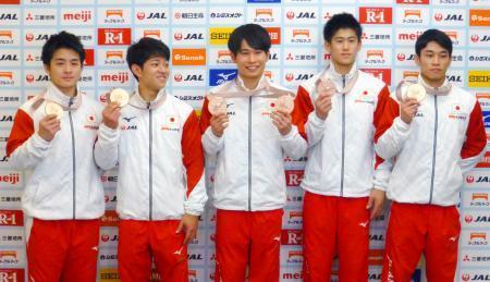 　体操の世界選手権から帰国し、記者会見でメダルを手にする（左から）神本、谷川翔、萱、橋本、谷川航＝１５日、成田空港