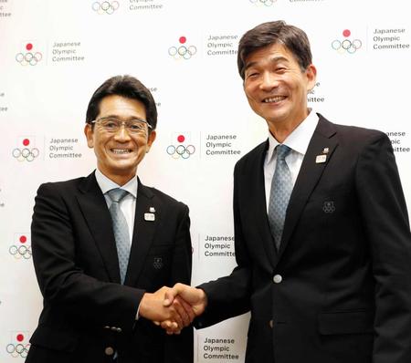 　笑顔で握手する、東京五輪の日本選手団団長に就任が決まった福井烈氏（左）と総監督を務める尾県貢氏