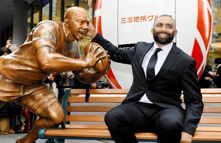 　自身の銅像の頭をなでるリーチ・マイケル