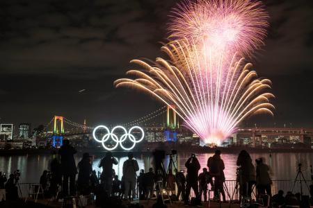 　東京五輪の開幕まで半年となり、お台場海浜公園の水上に設置された五輪マークのモニュメントがライトアップされ、記念の花火が祭典ムードを盛り上げた＝２４日夜、東京・お台場