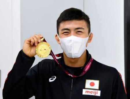 　優勝したアジア選手権から帰国し、笑顔でメダルを掲げるレスリングの文田健一郎＝２１日、成田空港
