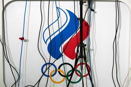 　２０１９年１２月、ドーピング問題での記者会見で掲示されたロシア五輪委のロゴ。報道陣のマイクの配線が垂れ下がる＝モスクワ（ＡＰ＝共同）