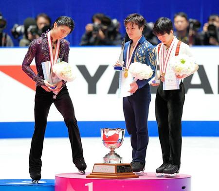 　昨年の全日本選手権で優勝カップを見つめる２位の羽生結弦（左）と優勝した宇野昌磨（中央）