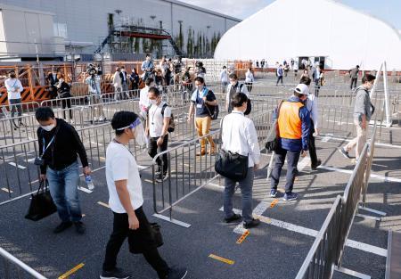 　東京五輪・パラリンピックに向けた手荷物検査エリア運営の実証実験で、間隔を空けて列に並ぶ人たち＝２１日午後、東京都江東区
