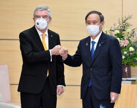 　会談を前にＩＯＣのバッハ会長（左）とグータッチを交わす菅首相＝１６日午前、首相官邸
