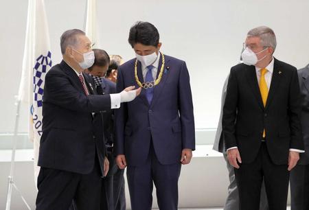 　安倍前首相（中央）に授与された「五輪オーダー」を見つめる東京五輪・パラリンピック組織委の森会長。右はＩＯＣのバッハ会長（代表撮影）