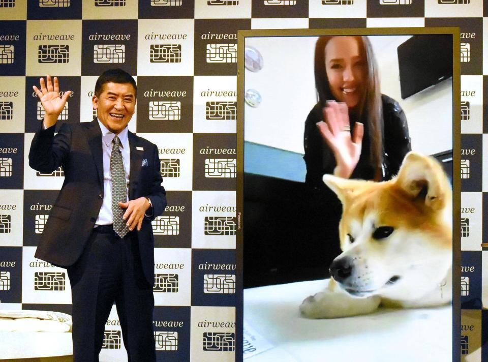 　株式会社エアウィーヴの高岡本州社長（左）と手を振るアリーナ・ザギトワと愛犬のマサル