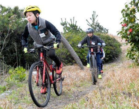 　「キッズトライアスロン教室」で、起伏のある松林を自転車で走る小学生＝１３日午後、鳥取県米子市