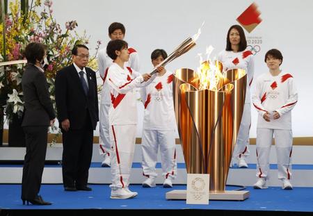 　聖火リレーの出発式で聖火皿からトーチへ点火する、２０１１年のサッカー女子Ｗ杯で優勝した日本代表「なでしこジャパン」のメンバー岩清水梓選手（代表撮影）