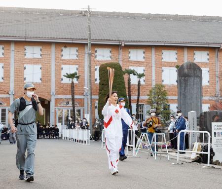 　富岡製糸場を背に聖火のトーチを掲げて走るタレントの井森美幸さん＝３１日午後、群馬県富岡市