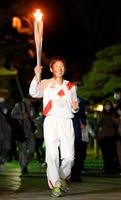 トーチを掲げて走る聖火ランナーの荻原健司さん＝１日夜、長野市