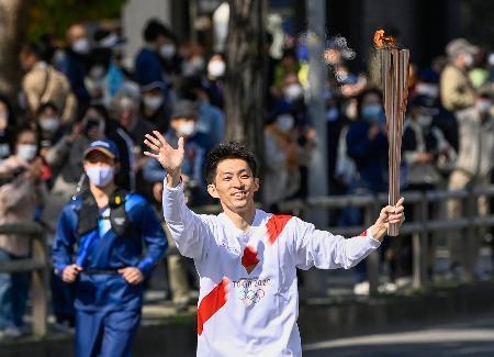 　聖火のトーチを掲げて走る田中和仁さん＝１０日午前、和歌山市