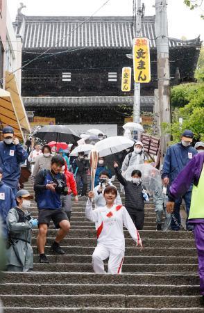 　香川県琴平町の金刀比羅宮大門（奥）前の石段で、トーチを掲げ聖火を運ぶランナー＝１７日午後