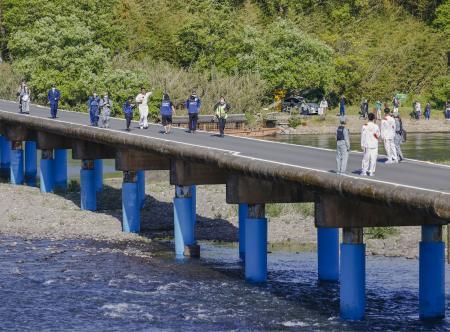 　四万十川に架かる沈下橋を走る聖火ランナー＝１９日午後、高知県四万十市