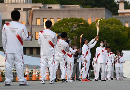 　松山市では新型コロナウイルス感染拡大の影響で公道での聖火リレーが中止となり、市内の公園で「点火セレモニー」が開かれた。走る機会がなくなったランナーがトーチで聖火をつないだ＝２１日午後