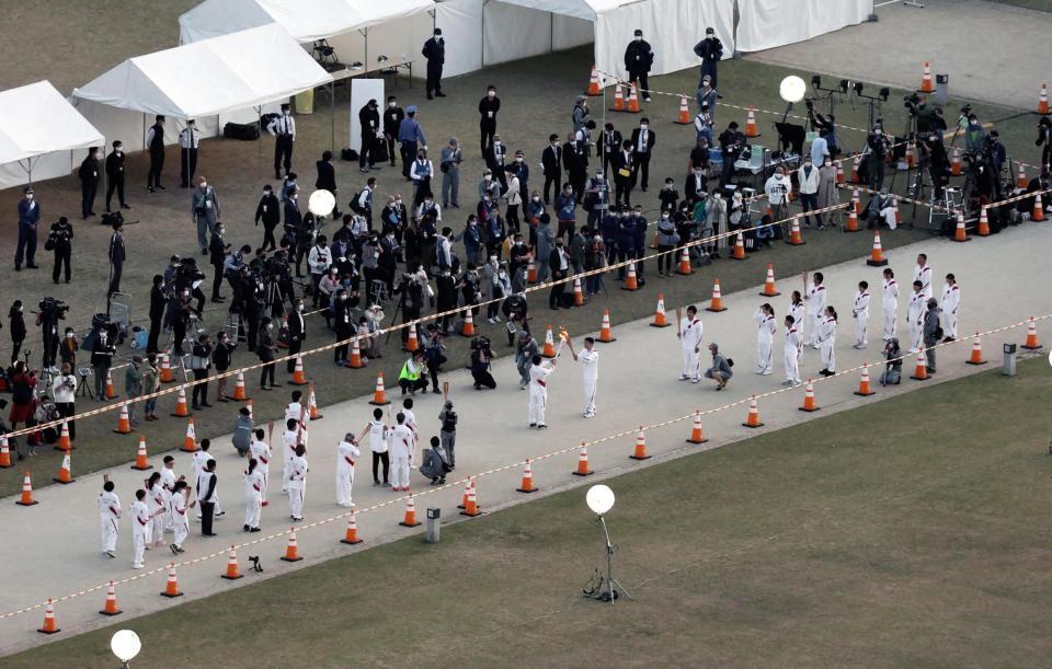 松山市では新型コロナウイルス感染拡大の影響で公道での聖火リレーが中止となり、市内の公園で「点火セレモニー」が開かれた。走る機会がなくなったランナーがトーチで聖火をつないだ＝21日午後