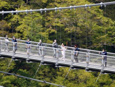 　大分県九重町の「九重“夢”大吊橋」で、トーチを掲げて走る聖火ランナー＝２４日午前