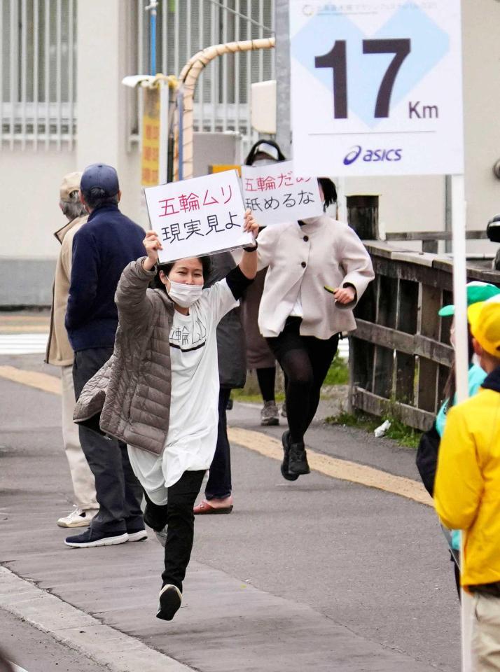 　東京五輪マラソンテスト大会のコース沿道で、「五輪ムリ」などと書かれたメッセージを掲げる人たち