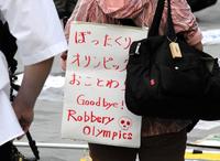 　国立競技場前で行われた五輪反対デモで「ぼったくりオリンピックおことわり」と書かれたボードを掲げる参加者
