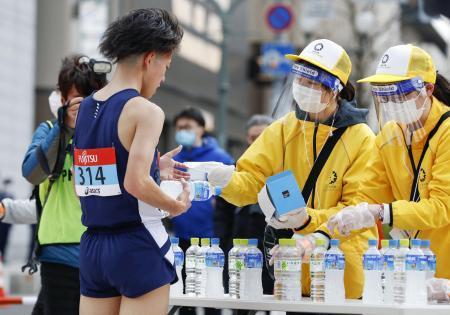 　東京五輪のテスト大会となる「札幌チャレンジ１０キロ」で、ゴールした選手にマスクを手渡すスタッフ＝５日、札幌市