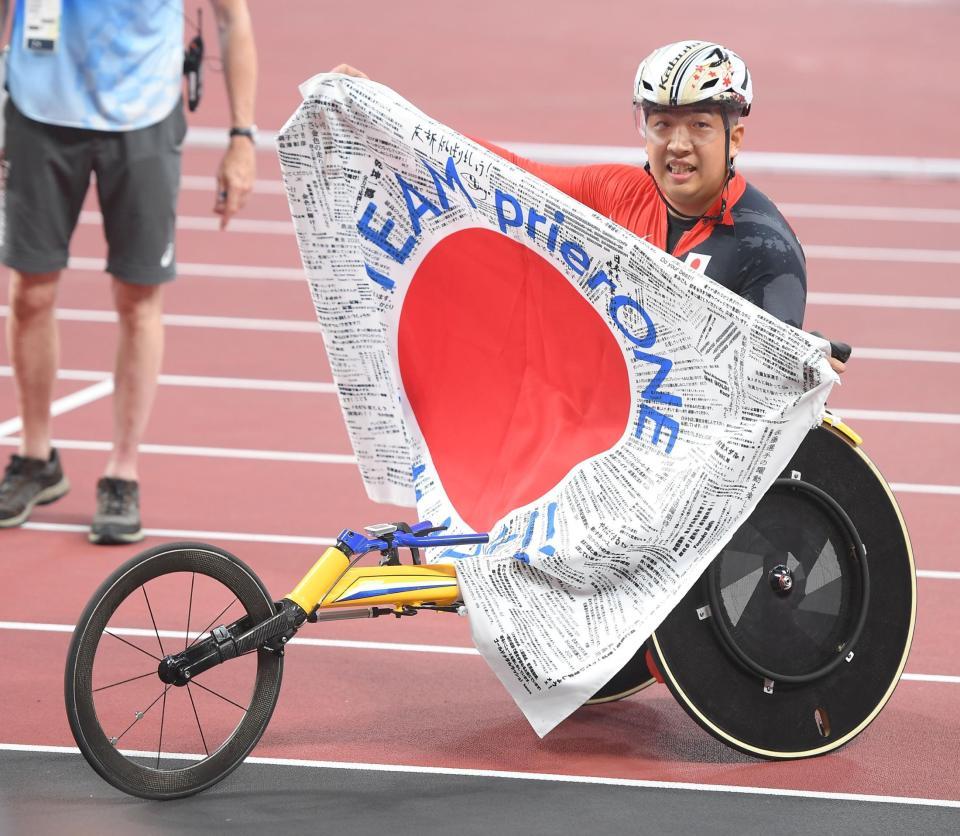 　陸上男子４００メートル（車いすＴ５２）決勝で金メダルを獲得し、応援の寄せ書きが入った日の丸を掲げる佐藤友祈（撮影・伊藤笙子）